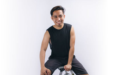 Portrait of young man standing against white background