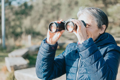 Side view of man photographing through binoculars