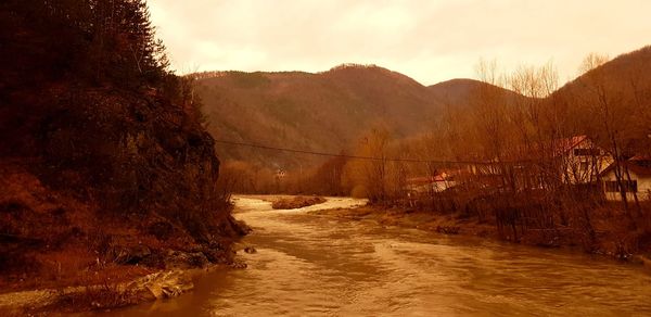 Scenic view of river amidst mountains against sky during sunset