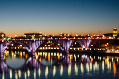 Illuminated bridge over river at night