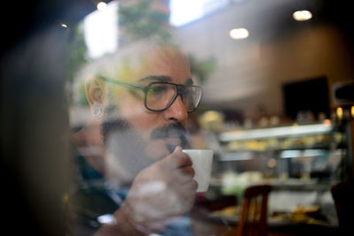 Man having coffee in cafe seen through window