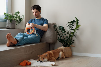 Adult man making diy homemade educational toys for dogs using a tutorial from the internet