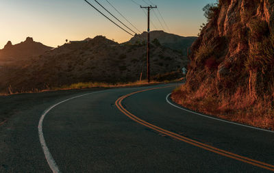 Country road by mountain against sky