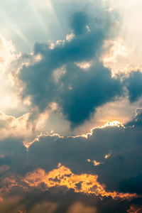 Low angle view of sunlight streaming through clouds