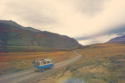 Scenic view of road by mountains against sky