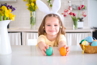 Portrait of cute girl sitting on table at home