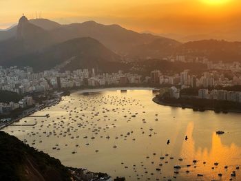 High angle view of river by buildings against sky during sunset