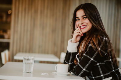 Portrait of a smiling young woman sitting at restaurant