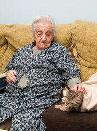 Senior woman with cat sitting on sofa at home