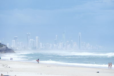 People at beach against buildings during foggy weather