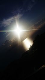 Sun shining through silhouette trees against sky during sunset