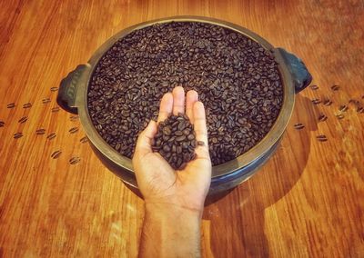 Cropped hand holding roasted coffee beans