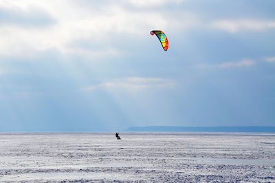 Person kiteboarding in sea against sky