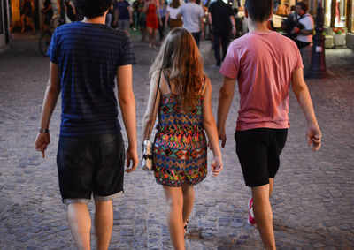 Rear view of people walking on footpath in city