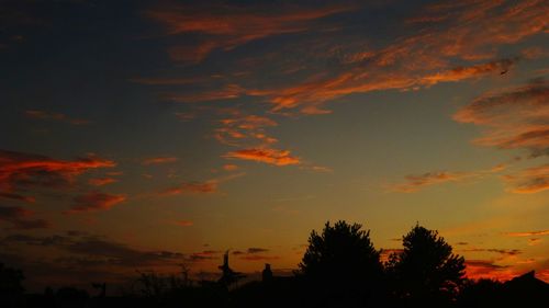 Low angle view of silhouette trees against dramatic sky