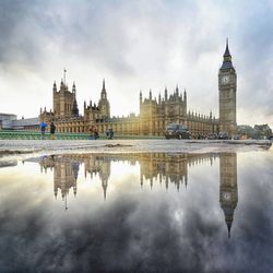 Reflection of big ben in puddle against sky
