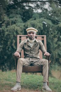 Portrait of man sitting on seat against trees