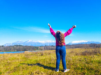 Full length of woman standing on field against blue sky