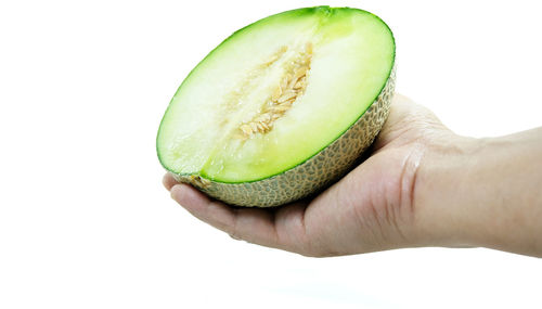 Close-up of hand holding apple against white background