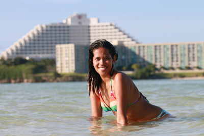 Portrait of smiling young woman at beach against sky