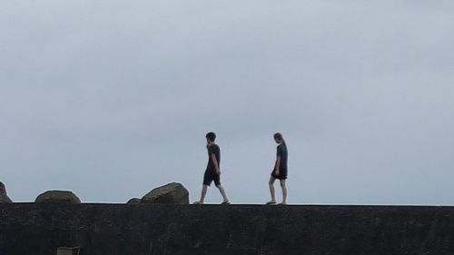 Low angle view of people walking against clear sky