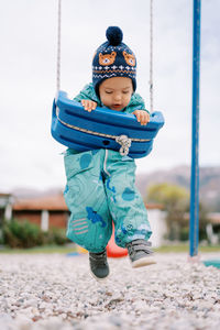Full length of boy swinging at playground