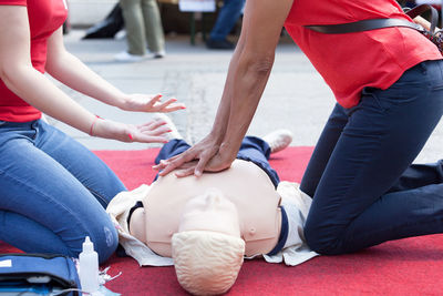 Instructor explaining rescue worker while giving cpr to mannequin