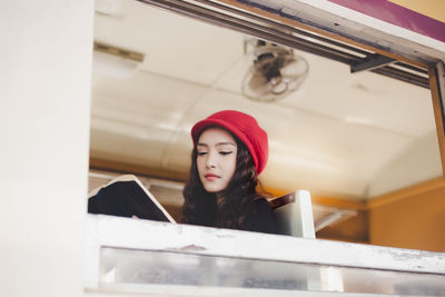 Portrait of young woman looking through window