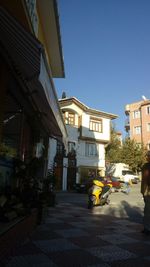 Street amidst buildings against clear blue sky