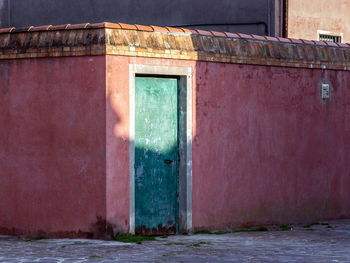 Sunlight falls on  this old wall with a weathered door in a small mediterranean town in the evening