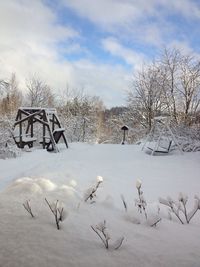 Frozen swing on field against cloudy sky