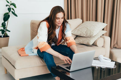 Young business woman works remotely online on a laptop in a cozy apartment.