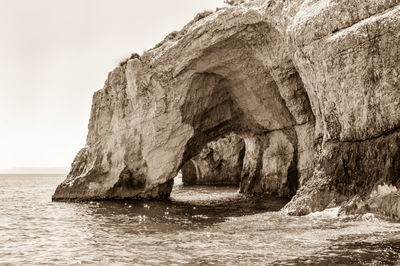 Rock formation in sea against sky