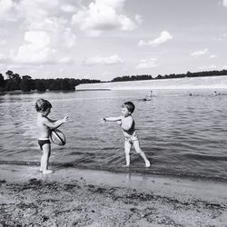 Full length of shirtless boys playing on shore at beach against sky