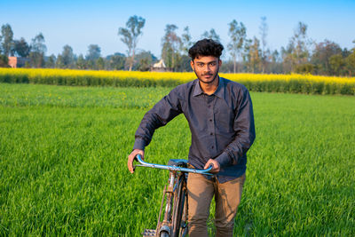 Portrait of man with bicycle on field