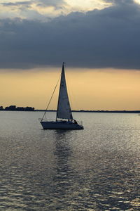 Boats sailing in sea at sunset