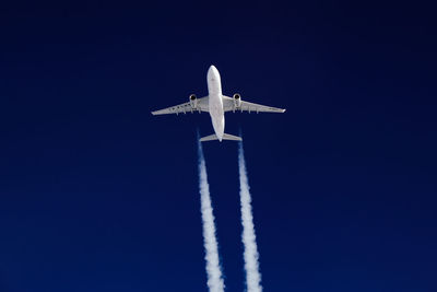 Low angle view of airplane flying against clear blue sky