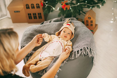 Mother playing with baby by christmas tree at home