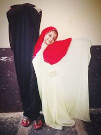 Portrait of smiling young woman standing against red wall