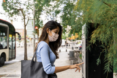 Woman in face mask purchasing bus ticket during covid-19