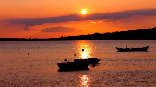 Silhouette boat in sea against orange sky