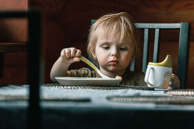 Portrait of boy holding coffee cup on table