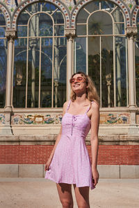 Portrait of smiling woman standing against built structure