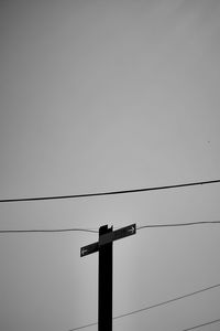 Low angle view of silhouette birds perching on cable against sky