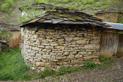 Stone wall of house and trees on field