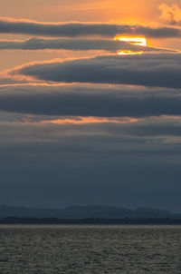 Scenic view of sea against dramatic sky during sunset