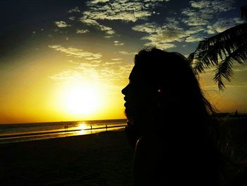 Silhouette man by sea against sky during sunset