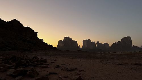 Rock formations by sea against clear sky during sunset