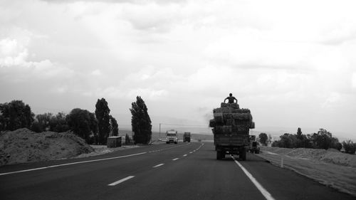 Road by trees against sky