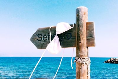 Clos-up of bikini top on directional sign against sea